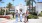 a group of people walking on a road with palm trees and a white building in the background with San Diego State University in the background